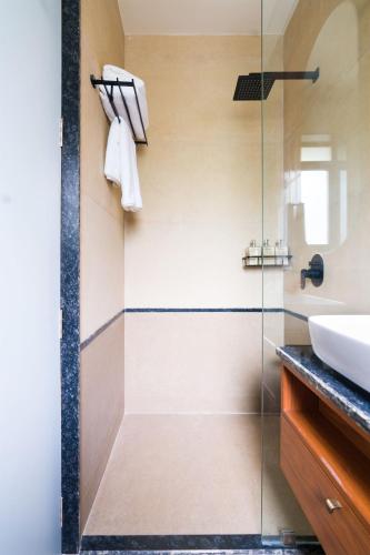 a bathroom with a shower with a sink and a mirror at SaffronStays Arabella in Alibaug