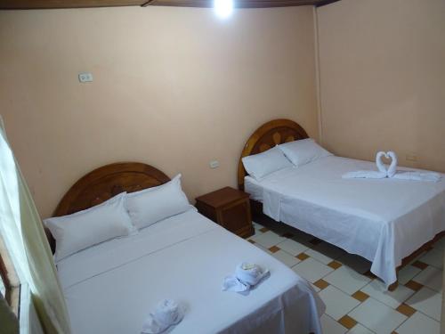 2 camas en una habitación con sábanas blancas en HOSTAL RESIDENCIAL UCAYALI, en Tingo María