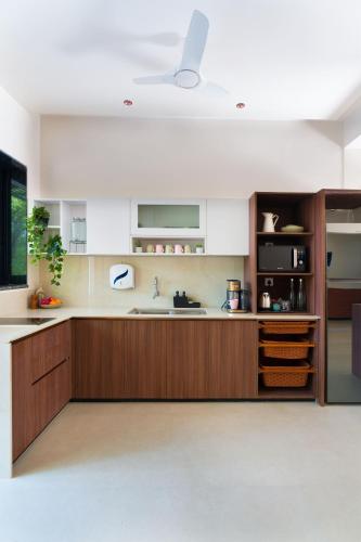 a kitchen with wooden cabinets and a sink at SaffronStays Arabella in Alibaug