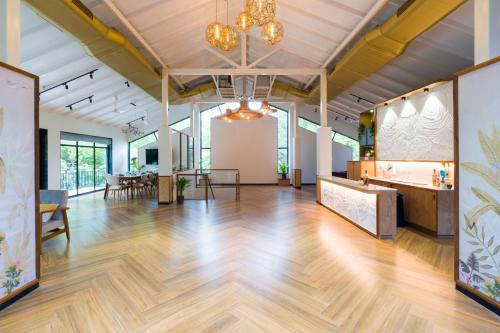 a large room with a wooden floor and tables and chairs at SaffronStays Arabella in Alibaug