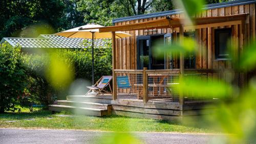 a tiny house with a chair and an umbrella at Camping Vesoul in Vaivre-et-Montoille