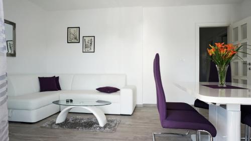 a living room with a white couch and purple chairs at Apartment L&A in Grebaštica