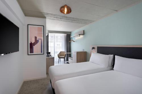 a hotel room with two beds and a desk at Hotel Mistral St Julian's, Affiliated by Meliá in St Julian's