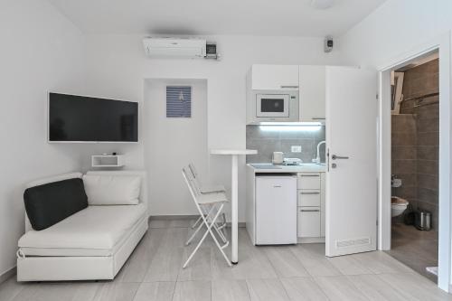 a white living room with a couch and a kitchen at Seagull Pool Apartments & Studios in Novalja