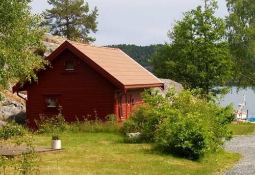 リソルにあるRisør Gjestehusの湖畔の小さな赤い小屋