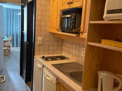 une cuisine avec un évier et un micro-ondes dans l'établissement Studio lumineux avec balcon et accès direct aux pistes, casier à skis - FR-1-181-2650, à La Plagne Tarentaise