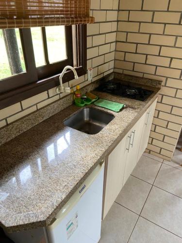 a kitchen counter with a sink and a window at Pousada Haras Trevo de Ferro, Praia, Piscina e Campo in Torres