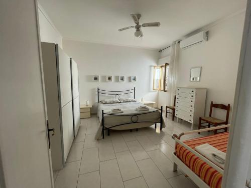 a white bedroom with a bed and a chair at Villetta SOLE in Torre Lapillo