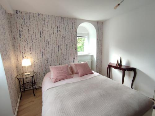 Un dormitorio con una cama con almohadas rosas y una ventana en Apartament 44, en Lądek-Zdrój