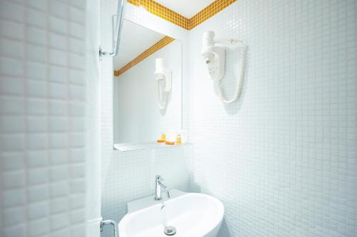 La salle de bains blanche est pourvue d'un lavabo et de toilettes. dans l'établissement Hôtel California, au Lavandou