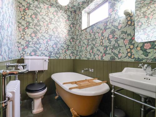 a bathroom with a toilet and a tub and a sink at Astondene in Southwold