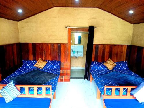 a room with two beds with blue sheets and a mirror at Misty Mountains Holiday Homes in Vattavada