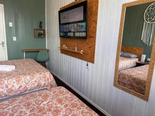 ein Hotelzimmer mit 2 Betten und einem Spiegel in der Unterkunft Quarto 6 no Centro de Itajaí, Ar+SmartTv in Itajaí