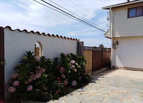 een wit hek met bloemen naast een huis bij OCEANO HOSTEL in Pichilemu