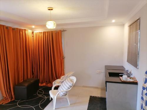 eine Küche mit zwei weißen Stühlen und einem orangenen Vorhang in der Unterkunft LadyMas Oasis in Goodhope