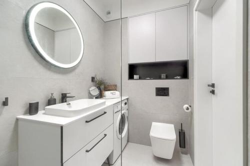 a bathroom with a sink and a toilet and a mirror at Ground floor apartment with a garden in Niechorze in Niechorze