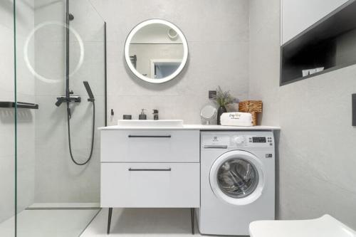 a white bathroom with a washing machine and a mirror at Ground floor apartment with a garden, close to the beach, Niechorze in Niechorze