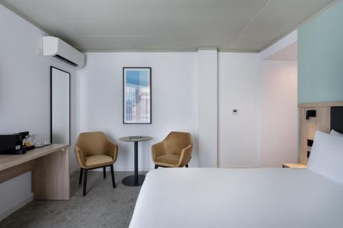 a bedroom with a bed and two chairs and a table at Hotel Mistral St Julian's, Affiliated by Meliá in St Julian's
