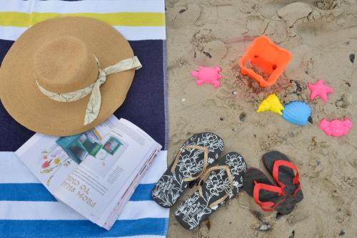 a hat and flip flops on the beach with a book and a pile at dk villas 1 Harbour View Hout Bay in Hout Bay