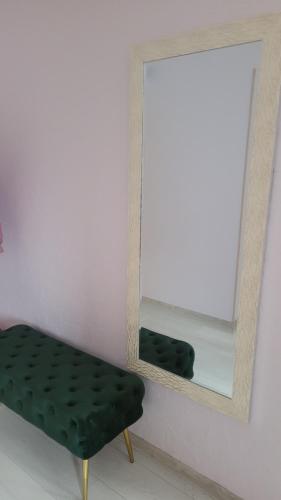 a mirror and a green bench in a room at Dzintara apartamenti in Kuldīga