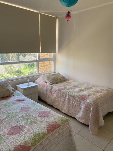 two beds sitting in a room with a window at Hermoso depto Lomas de Papudo 2 in Papudo