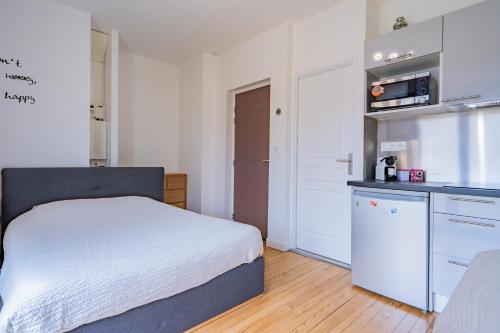 Cet appartement comprend une chambre avec un lit blanc et une cuisine. dans l'établissement Room in Toulouse - Studio 1 proche Airbus à TOULOUSE ST Martin du Touch, à Toulouse