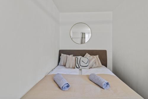 a bedroom with a bed with two pillows and a mirror at Stylish Flat, next to Handelskai in Vienna
