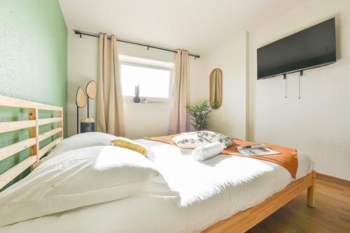 une chambre avec un lit avec une télévision au mur dans l'établissement Le Studio - Tramway, à Strasbourg