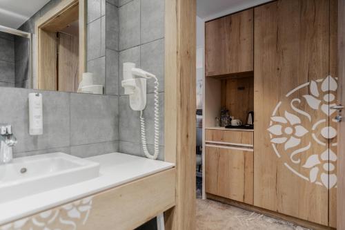 uma casa de banho com um lavatório e um telefone na parede em Hotel Aquarion Family & Friends em Zakopane