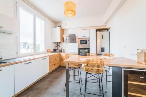 une cuisine avec des armoires blanches et une table avec des tabourets dans l'établissement Le Général d'Or - 2 Chambres, à Brive-la-Gaillarde