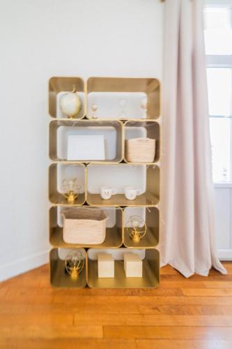 une étagère remplie de plats et de bougies à côté d'une fenêtre dans l'établissement Le Général d'Or - 2 Chambres, à Brive-la-Gaillarde