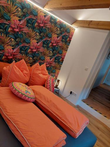 an orange couch in a room with a floral wall at Hufschmieds Bleibe in Passau