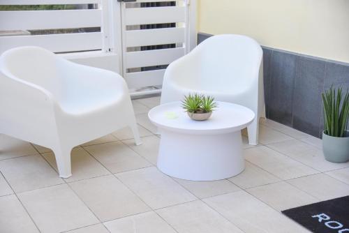 two white chairs and a plant on a floor at Shanti Rooms & Apartments Risorgimento in Bacoli