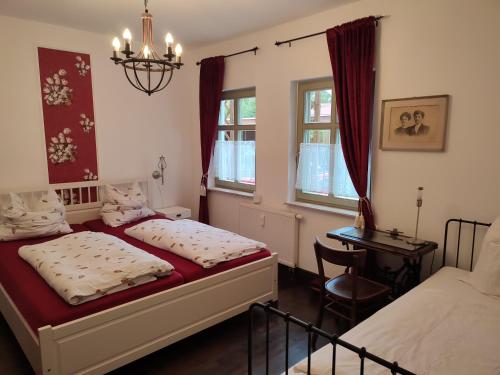 a bedroom with two beds and a table and a chandelier at Ferienwohnung Birkenwerder bei Berlin in Birkenwerder