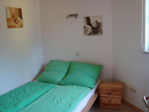 a bed with green sheets in a small room at Bungalow-Gelb-Peters in Börgerende-Rethwisch