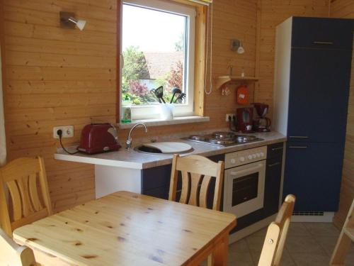 een keuken met een tafel, een fornuis en een raam bij Bungalow-Gelb-Peters in Börgerende-Rethwisch