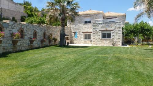 a stone house with a palm tree in a yard at Infinity Blue Villa in Koroni