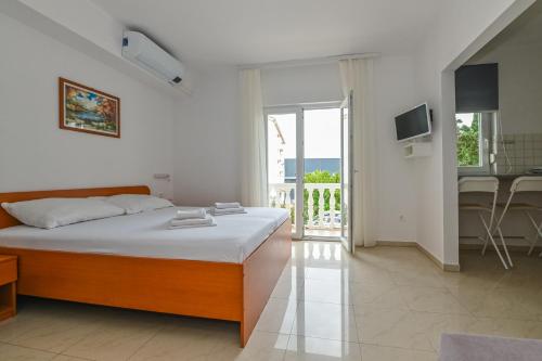 a white bedroom with a bed and a balcony at Seagull Pool Apartments & Studios in Novalja