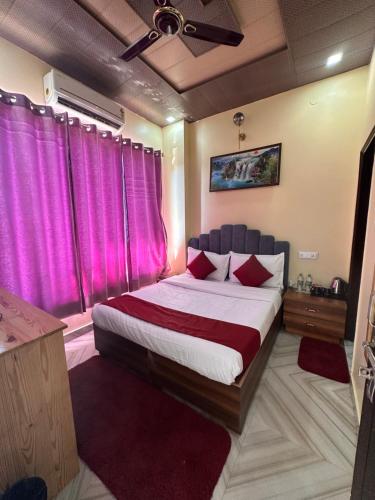 a bedroom with a large bed with pink curtains at The Peninsulla in Rishīkesh