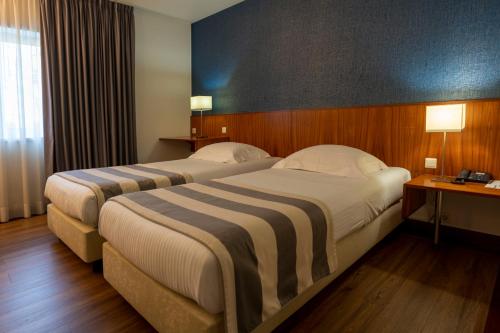 two beds in a hotel room with two lamps at Hotel Villa Garden Braga in Braga