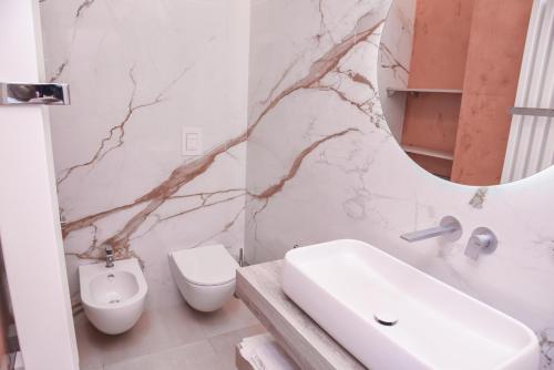 a bathroom with a sink and a toilet and a mirror at Shanti Rooms & Apartments Risorgimento in Bacoli