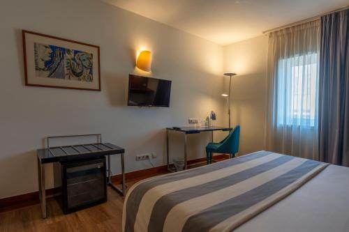 ブラガにあるHotel Villa Garden Bragaのベッド、デスク、テレビが備わるホテルルームです。