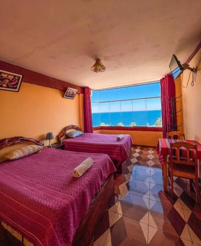 a bedroom with two beds and a large window at Hostal Sol y Lago in Copacabana