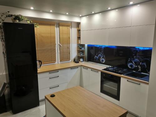 a kitchen with white cabinets and a black refrigerator at Jacuzzi Apartament in Toruń