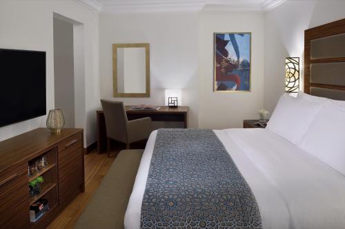 ein Hotelzimmer mit einem großen Bett und einem Schreibtisch in der Unterkunft Marriott Executive Apartments Al Khobar in Khobar
