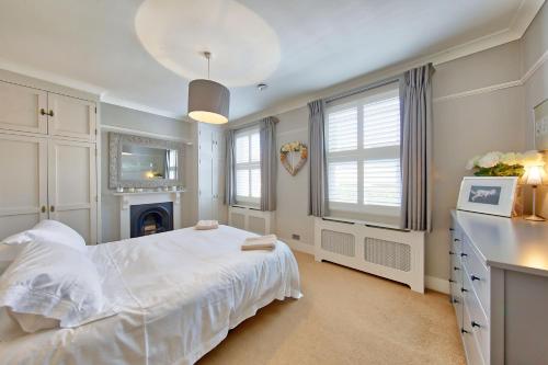 a white bedroom with a bed and a fireplace at House - Sleeps 8 - Garden - Children's Play Area in London