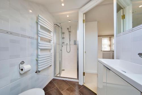 ein Bad mit einer Dusche, einem WC und einem Waschbecken in der Unterkunft Family 4-Bed House & Secluded Garden - Wimbledon in London