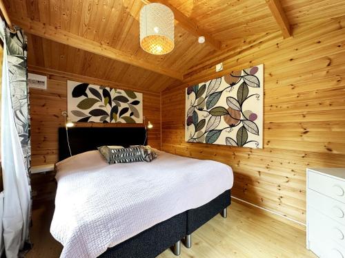 1 dormitorio con 1 cama en una habitación de madera en Nice holiday home by the lake Vristulve, en Timmersdala
