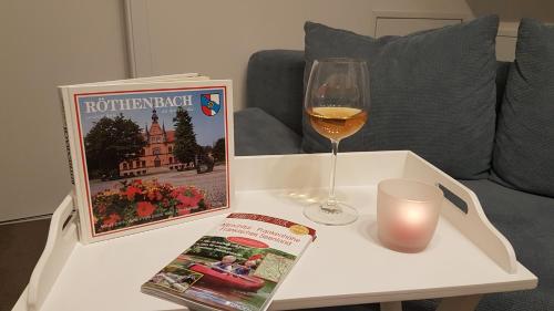 a table with a glass of wine and a magazine and a candle at Gemütliche Gäste-/Messewohnung 350 m. zur S-Bahn in Röthenbach an der Pegnitz