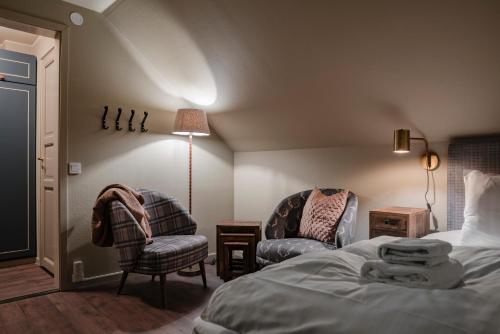 a bedroom with a bed and two chairs and a lamp at Trillevallens Högfjällshotell & Lägenheter in Trillevallen
